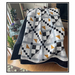 The finished Diamond Mist quilt by Pleasant Valley Creations in black, white, and yellow fabrics draped over a couch in a cozy home environment. 