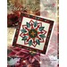 A festive quilt design featuring a star-shaped flower with red, green, and white geometric patterns.