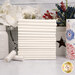A stack of the fabrics included in the Star Spangled Whites collection with a jar and a basket and flowers and a vase and a candle and thread.
