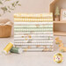 A stack of the fabrics included in the Our Little Adventure collection, with a bookshelf and a basket and a plant and duck toys and thread.