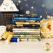 A stack of the fabrics included in the Lumière collection, with flowers and lights and a lantern and a butterfly and thread.