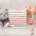 A stack of the fabrics included in the Purrfection Flannel collection, with flowers and a mug and a cat plush and thread and yarn.