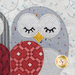A super close up on the owl's eyes, showing details on the fabrics, prints, and hand-embroidered finishing touches.