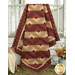 The completed Log Cabin Throw Quilt colored in rich red and deep tan fabrics from the Dear Scarlet collection by Marcus Fabrics, hung on a farmhouse porch railing and staged with coordinating flowers and furniture.