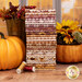 A stack of the fabrics included in the Harvest on the Prairie collection, with flowers and pumpkins and a vase and leaves and thread and a window.