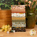 A stack of the fabrics included in the Worth Repeating collection, with flowers and a pitcher and boxes and thread and greenery.