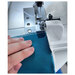 Close-up image of a serger machine and blue fabric.