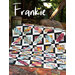 Colorful quilt titled Frankie displayed outdoors on a textured surface with lush greenery.