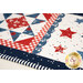 A super close up shot of the corner of the patchwork block intersecting with the laser cut scallop border and scattered stars, demonstrating piecing and stitching detail. 