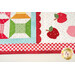 A super close up shot of the corner of the thread spool block intersecting with the laser cut scallop border and appliqué apples, demonstrating piecing ad stitching detail. 
