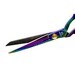 Close-up of colorful, metallic scissors with a gold pivot screw and engraved details on the handle.
