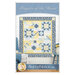 The front cover of the Prayers of the Heart pattern. A finished a blue and yellow quilt hangs on a white paneled wall with coordinating décor on the front cover. 