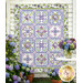 The completed Bouquet of Hydrangeas Quilt, colored in powder blue, purple, green, and white fabrics from the Hydrangeas in the Garden collection from Riley Blake Designs, hung on a rustic white shiplap wall and staged with full bloom hydrangeas. 