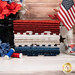 A stack of the fabrics included in the American Valor FQ bundle, with a flag and vases and flowers and buttons and thread.