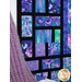 A stylized shot of the Stained Glass patchwork of the quilt, showing details on the color, print, and top quilting. A purple knit blanket sits in the foreground. 