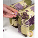 A model's hand shows details on the zipper pull charm; details on the fabric colors and prints can be seen.
