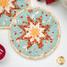 A close up on the round hot pad, demonstrating color and print details on the light blue, red, and peach fabrics.