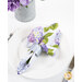 A shot of one of the napkins with the floral print faced out, staged on a white plate with a brushed nickel napkin ring.