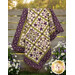 The completed Patchwork BOM quilt, colored in beautiful beige, green, and plum purple fabrics from the Collection for a Cause: Essence collection by Moda Fabrics, artfully draped over a wooden fence between daisies and lavender.