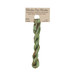 A skein of light kelly green and brown embroidery floss, twisted and bundled, with a tan label featuring the brand name and color information.