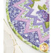 Slightly angled view of table topper featuring a patchwork design of fabrics in lilac purple and green. 