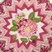 A top-down view of the center of the table topper showing  a patchwork design of fabrics in light pink and fuchsia.