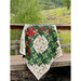 Image of the quilt draped over a wooden railing in a green field