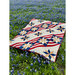Image of the completed quilt laying in a field of grass and purple flowers