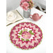 A round table topper with a bursting star design in light pink and fuchsia fabrics with blooming pink hydrangeas at the center placed on white table next to a teapot and cup and a bouquet of flowers. 
