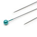 Close up shot of a teal pearlized pin head in-between two pointed end needles.