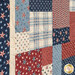 Close-up of a quilt featuring red, white, and blue patchwork with star and striped patterns.