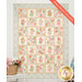 The completed Patchwork Panel Quilt colored in the Sunbonnet collection from Moda Fabrics, hung on a white paneled wall with coordinating florals and décor on either side of the quilt.
