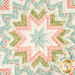 A top-down view of the center of the table topper showing a patchwork design of fabrics in peach, cream, teal, and green.