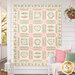 The completed Baltimore Panel Quilt colored in pastel florals from the Kindness collection, hung on a white paneled house with a wrap around porch with coordinating décor. 