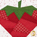 A super close up on the center of the strawberry, showing details on the red and green fabrics as well as the white background fabric.