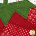 A super close up on the top of the strawberry, showing details on the red and green fabrics as well as the piecing. 