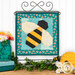 The completed Foundation Paper Piecing Series 4 August project, a teal and yellow design of a bumblebee, displayed on a craft stand and staged with coordinating décor.