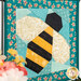 A close up on the paper pieced bee, showing details on the fabrics including the gold glitter wings.