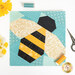 A stylized top down shot of the unfinished bee block, staged on a white countertop with coordinating notions and flowers.