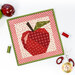 A top down shot of the project on a white background, staged with thread, scissors, and a decorative apple.
