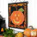 An angled shot of the October project, hung from a display hanger, staged with coordinating Halloween décor.