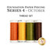 Four spools of orange, yellow, green, and brown thread, isolated on a white background. 