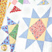 A close up on the draped quilt, demonstrating fabric colors, prints, and form of the quilt.
