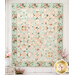 The completed Rose Hill Lane Quilt, colored in gentle mint, blue, cream, and pink vintage fabrics from the Rose & Violet's Bouquet des Fleurs collection by Riley Blake Desings, hung on a white wood wall and staged with coordinating flowers.