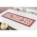 The completed Patchwork Table Runner colored in pink fabrics from the Hydrangeas In The Garden collection from Riley Blake Designs, staged on a white table.
