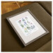 A digital mock-up of the completed Botanical Sampler Cross Stitch kit framed and laying on a couch.