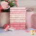 A stack of pink and cream patterned fat quarters from the Sweet Pink collection staged next to a pink vase with flowers and sewing supplies.