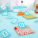 Crafting workspace with colorful fabric squares, alphabet clips, scissors, and assorted buttons.
