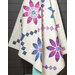 Quilt featuring large purple and blue flowers with geometric patterns, draped over a display stand.