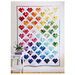 The completed Scrappy Love quilt finished and hung on a white wall.